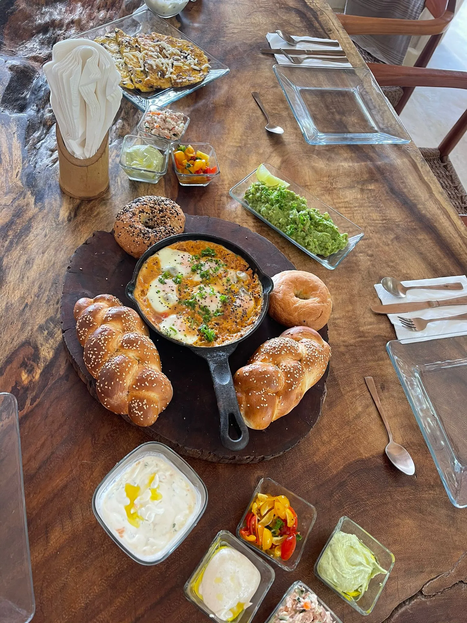 Shakshuka in a cast-iron pan with fresh-baked challah and kosher mezze on a wooden table